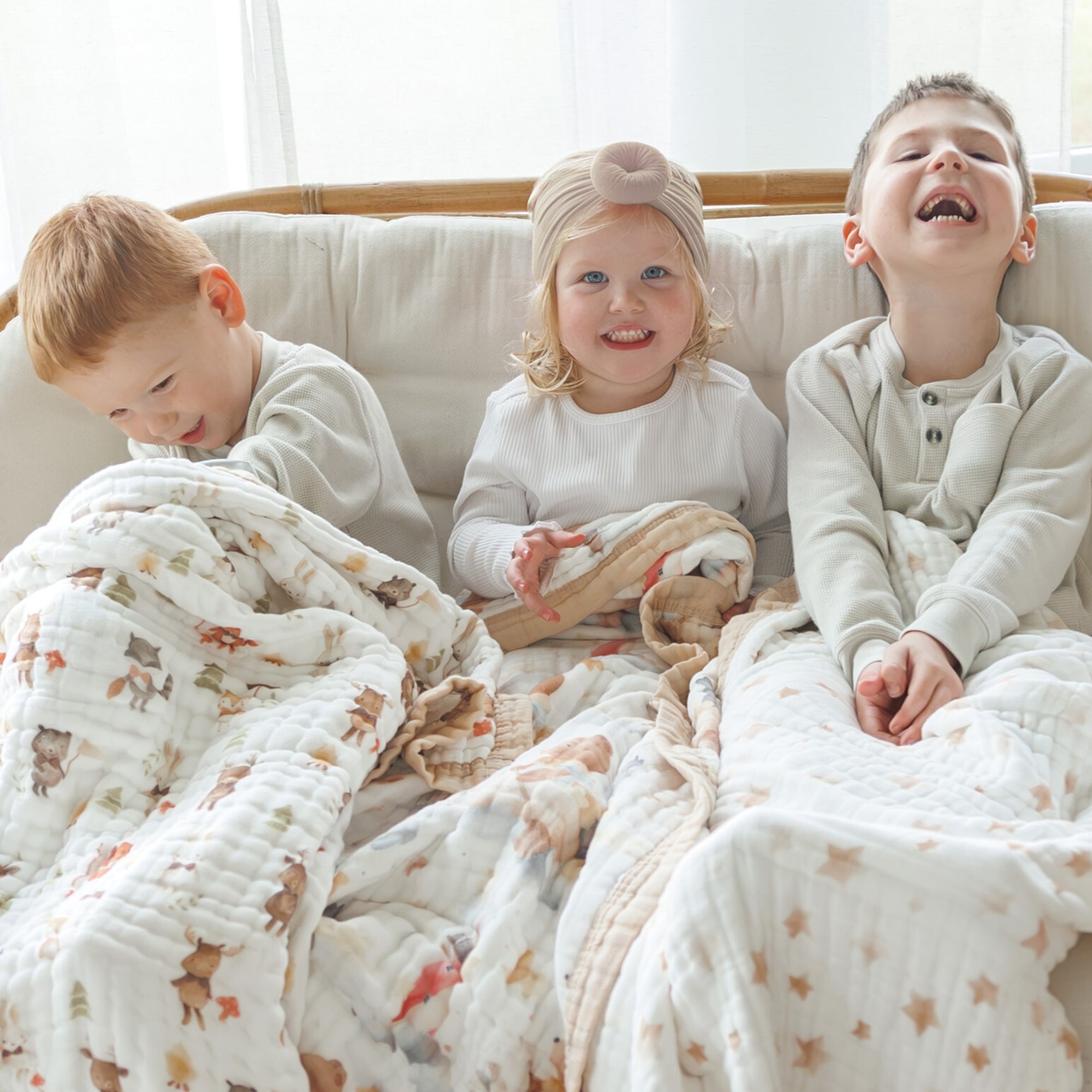 Organic Cotton Toddler Blankets by Natchiketa with three kids laughing and playing with the blankets