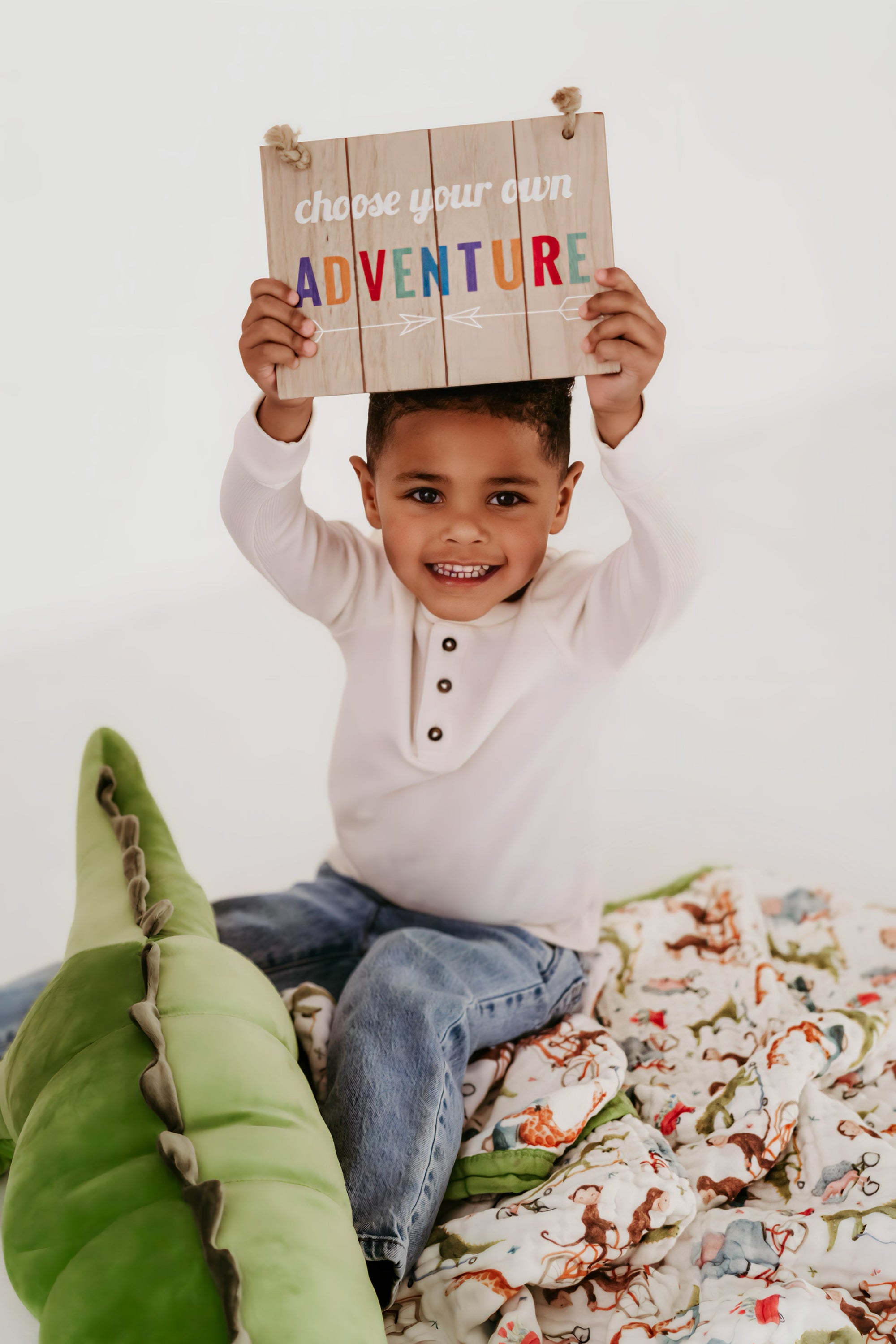 Kid showing the choose your adventure board sitting on top at Natchiketa blanket