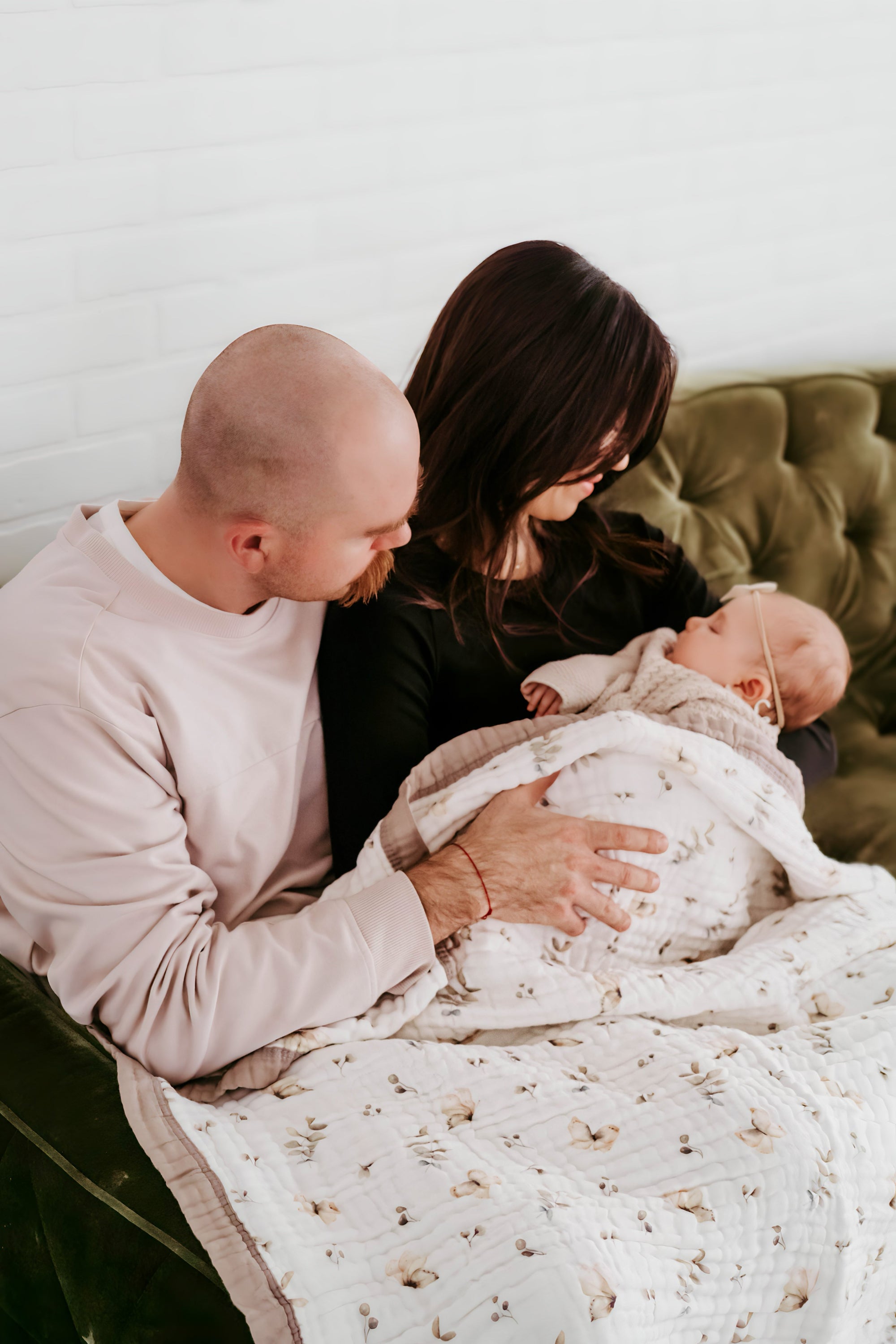 Parents looking at their infant wrapped in Natchiketa Blanket